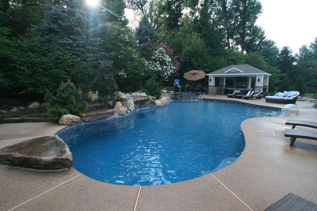 blue pool with outdoor cabana and natural boulder waterfall